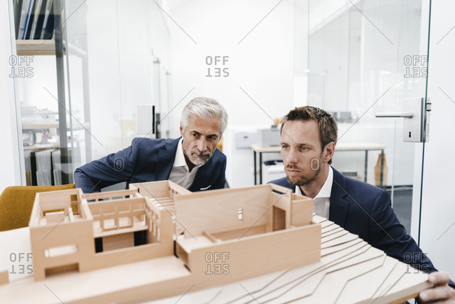 Two businessmen examining architectural model in office