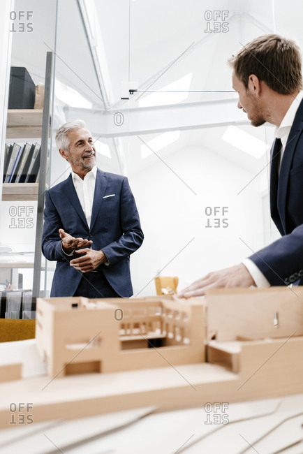 Two businessmen with architectural model in office