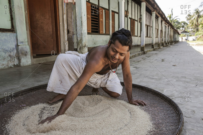 October 24, 2016: A Satra Boy Spreading Rice On Big Hand Woven Tray To Feed Birds, Assam, India