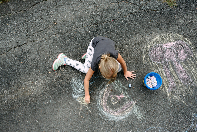 Little girl making a chalk drawing on the street