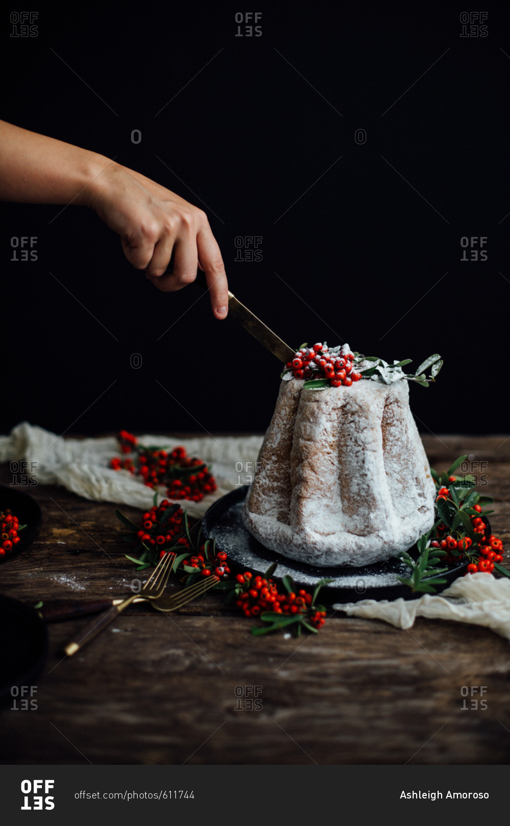 Woman slicing a holiday cake toped with powdered sugar and berries