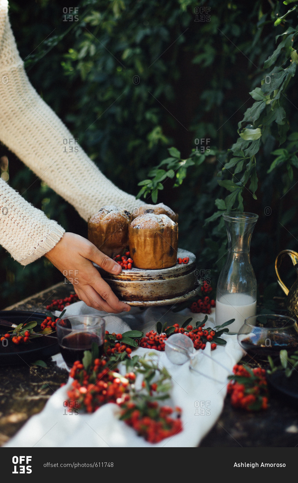 Woman placing holiday mini cakes on an outdoor table with berries
