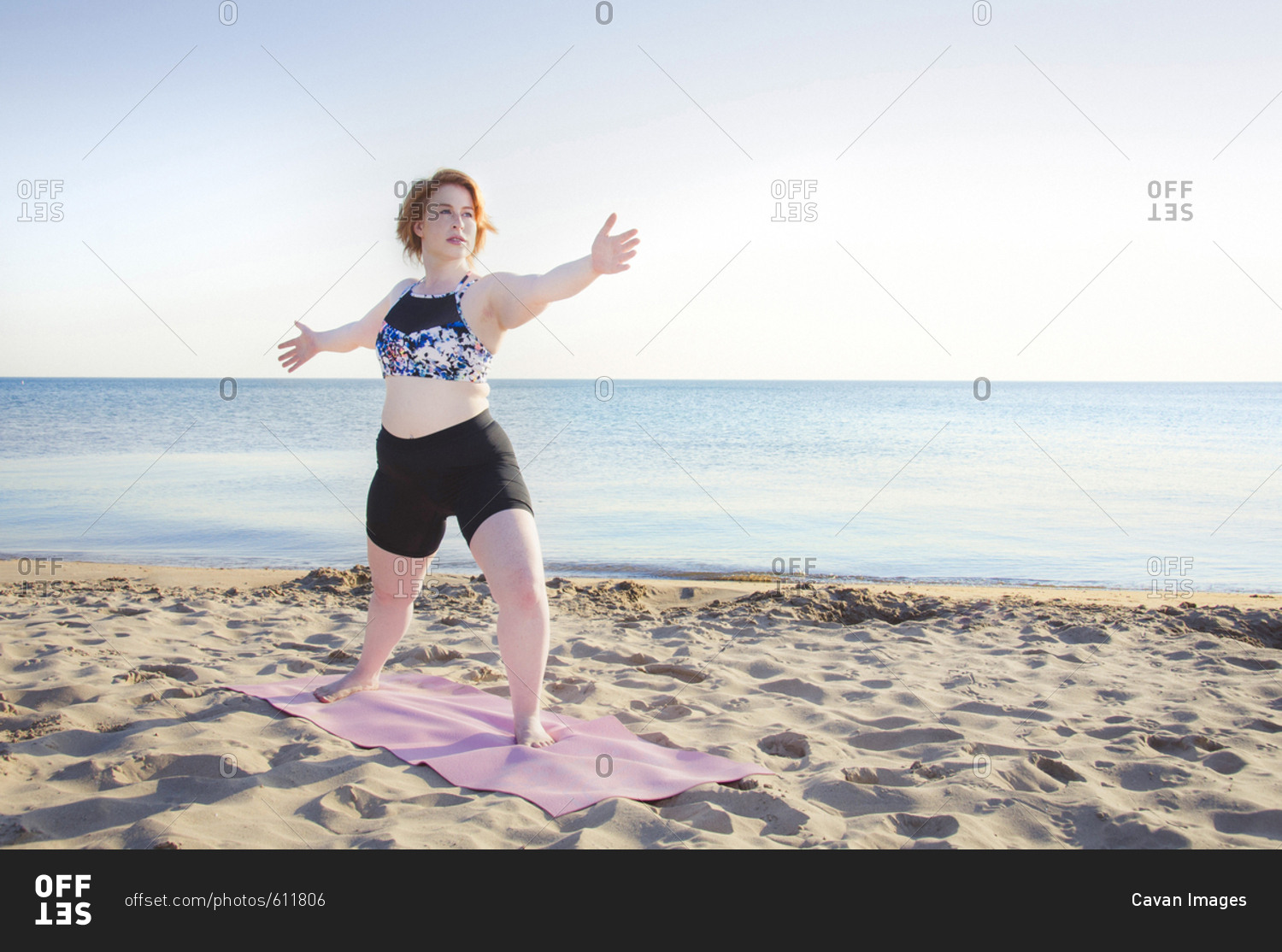 Woman practicing yoga pose at beach against clear sky stock photo - OFFSET