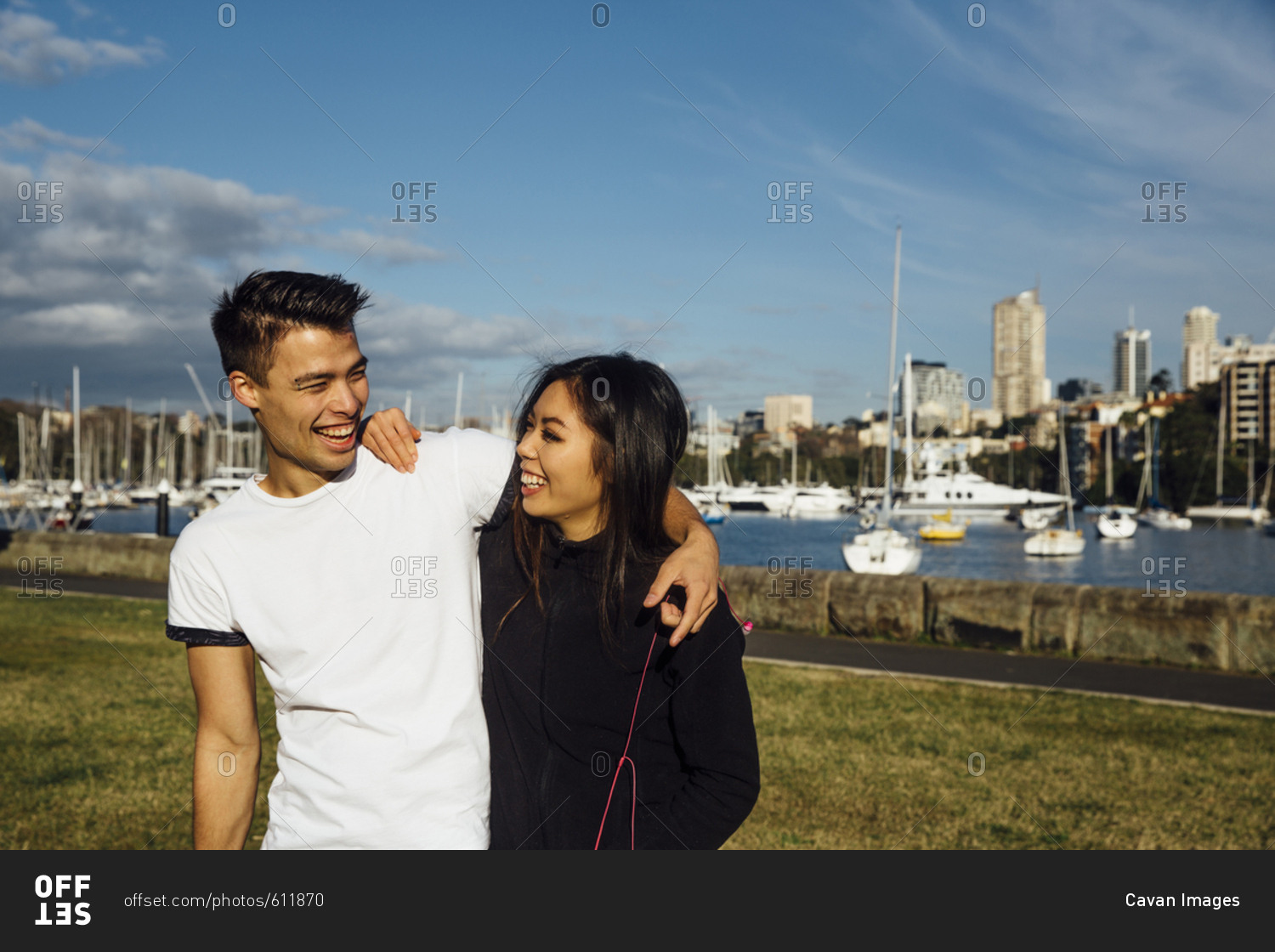 Happy young couple standing with arms around shoulder while exercising in city