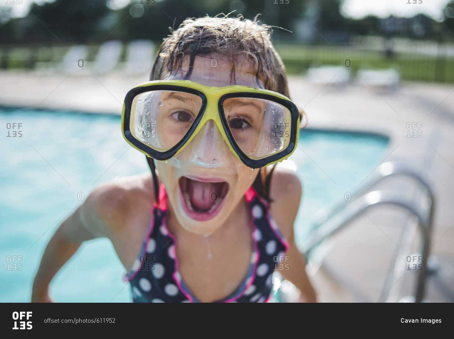 Portrait of girl with mouth open wearing swimming goggles while standing on poolside
