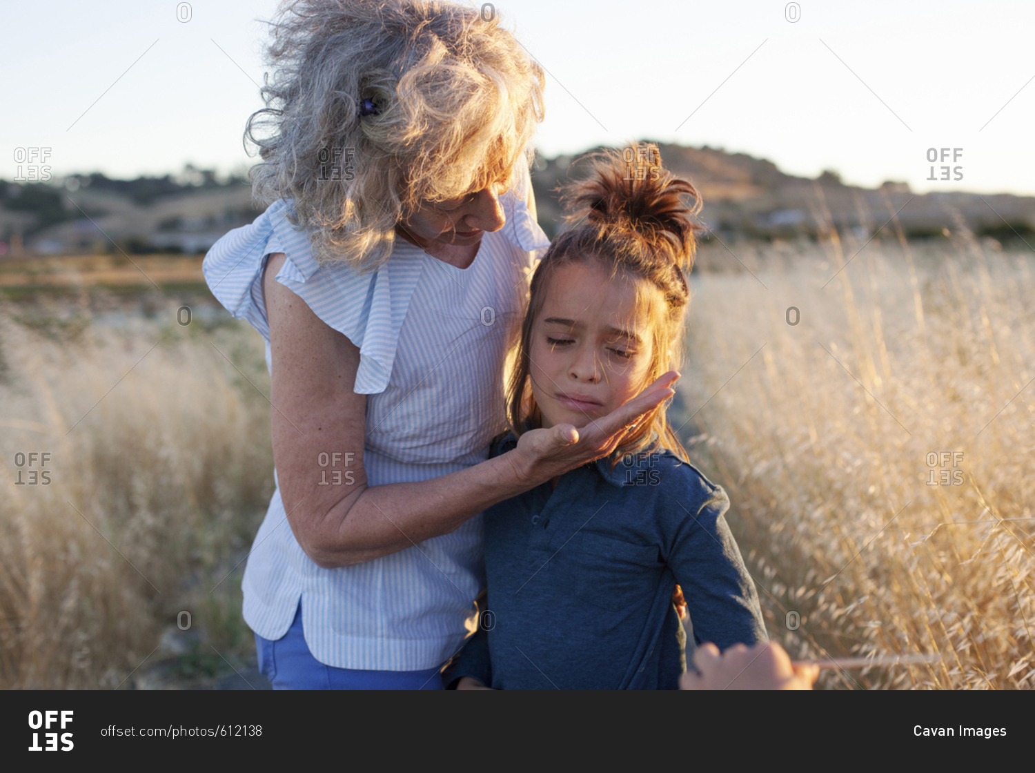 Grandmother consoling crying grandson while standing on field