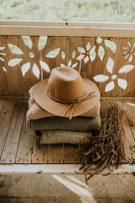 Hat on stack of folded blankets beside dried plants
