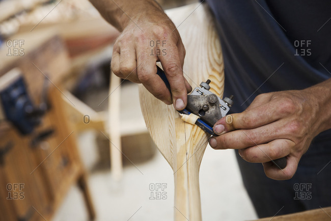 Close up of person working in a boat-builder\'s workshop, working on a wooden oar
