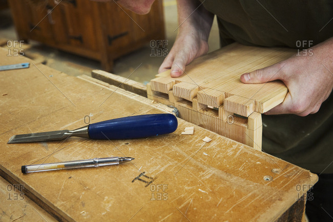 Close up of person working a boat-builder's workshop, joining together two pieces of wood