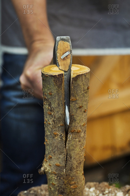A wood carver splitting small log of wood in half with an axe