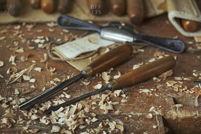 Close up of wood carving hand tools, chisels and wood shavings on a bench in a carver's workshop