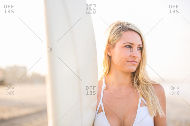Woman taking off her shirt to reveal a bikini swimsuit top stock photo -  OFFSET