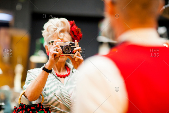 Quirky vintage woman photographing boyfriend on vintage camera in antiques emporium