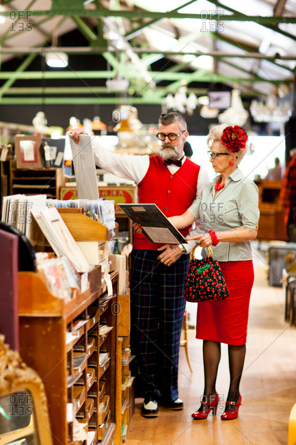 Quirky vintage couple looking at pictures in antique and vintage emporium