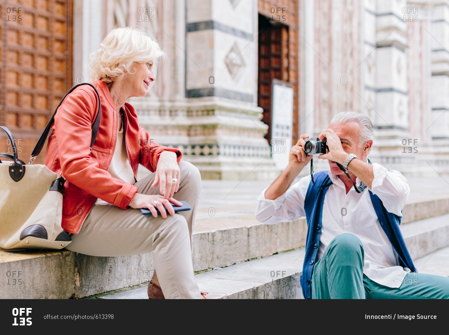 Senior male tourist photographing wife on Siena cathedral stairway, Tuscany, Italy