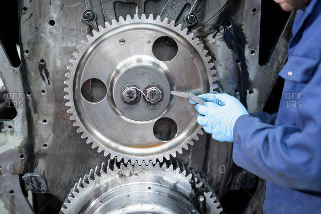 Engineer using feeler gauge on engine parts of locomotive in train works