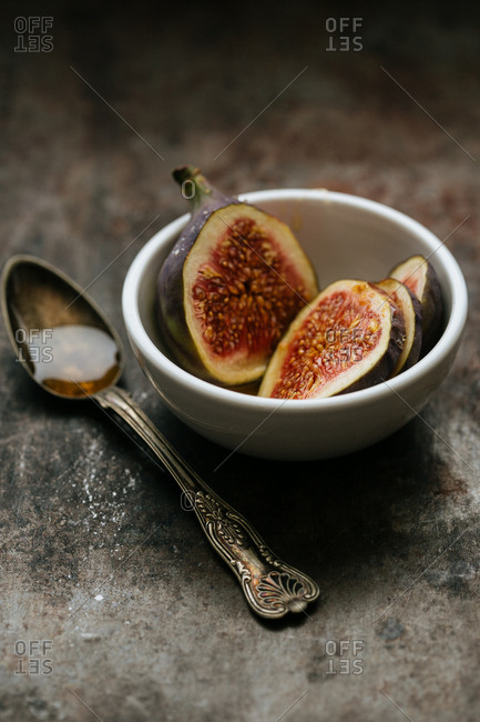 Sliced figs in a bowl and a spoonful honey