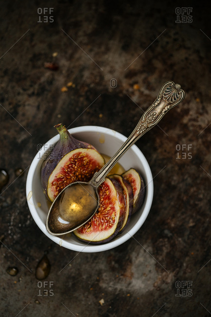 Sliced figs in a bowl with a spoonful honey