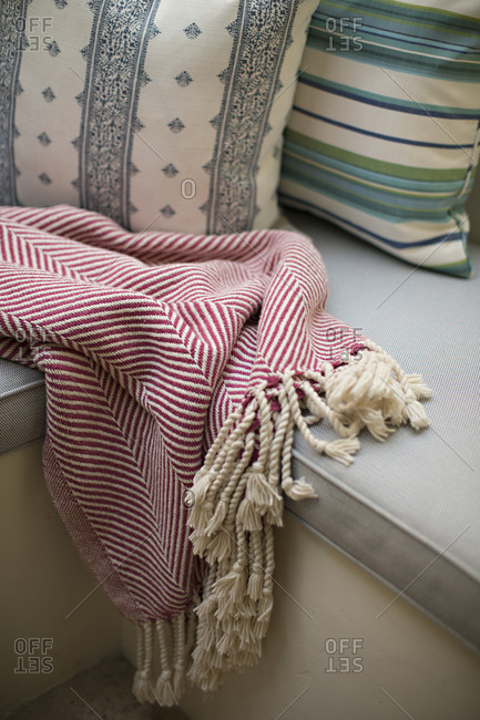 Bred blanket with tassels on seat with cushion and pillows