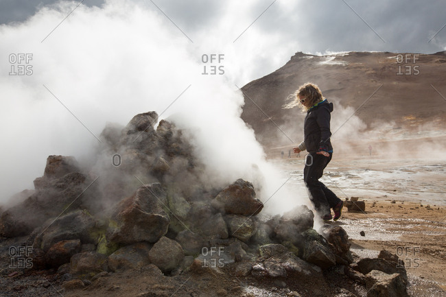 A woman walks among the steaming mud pots geothermal area near Lake Myvatn