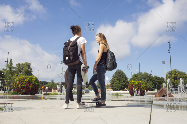 Teenage girl (14-15) and teenage boy (16-17) hanging out in skateboard park