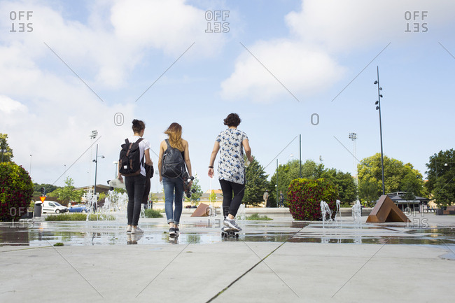 Rear view of teenage girls (14-15) and teenage boy (16-17) hanging out in skateboard park