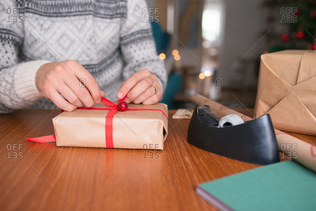 Man wrapping gift with red ribbon