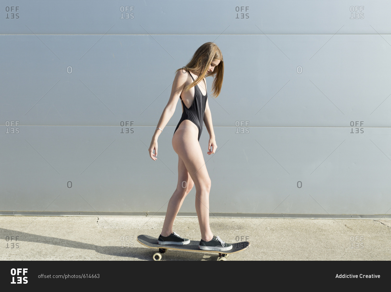 Girl in swimsuit on skateboard at street