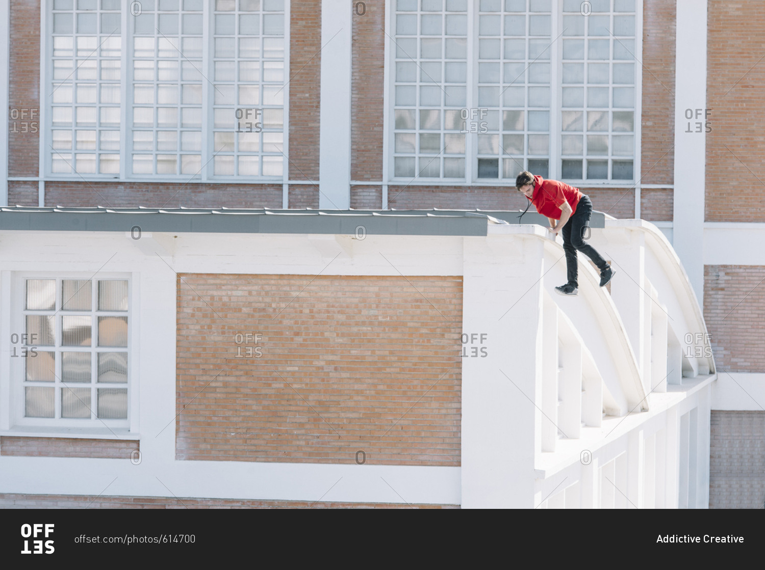 Side view of man doing parkour climbing on urban roof in sunny day.