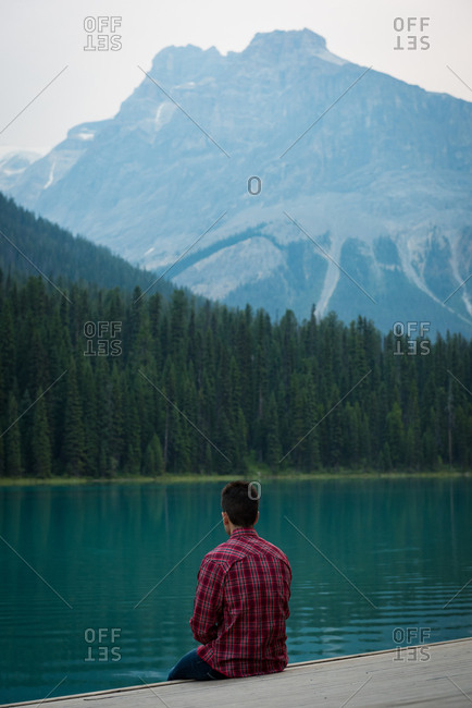Rear view of man sitting near the lake