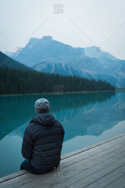 Rear view of man sitting near the lake