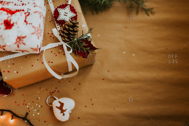 Christmas presents wrapped in ordinary and white paper and decorated with white ribbon, pine cone, and star felt ornament