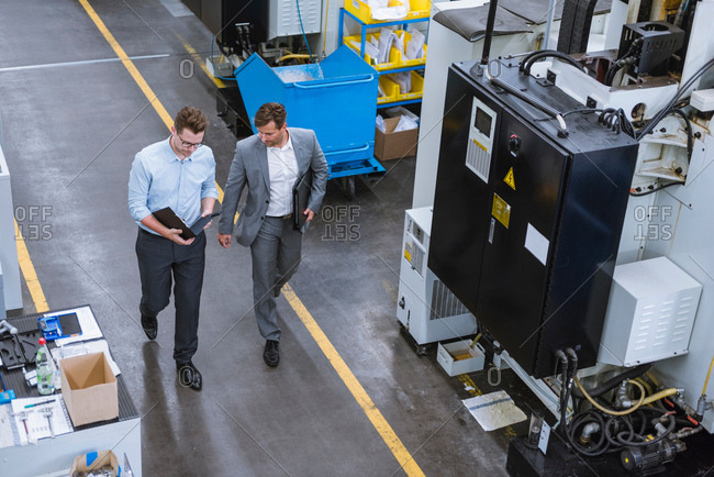 High angle view of two male managers walking and talking in factory