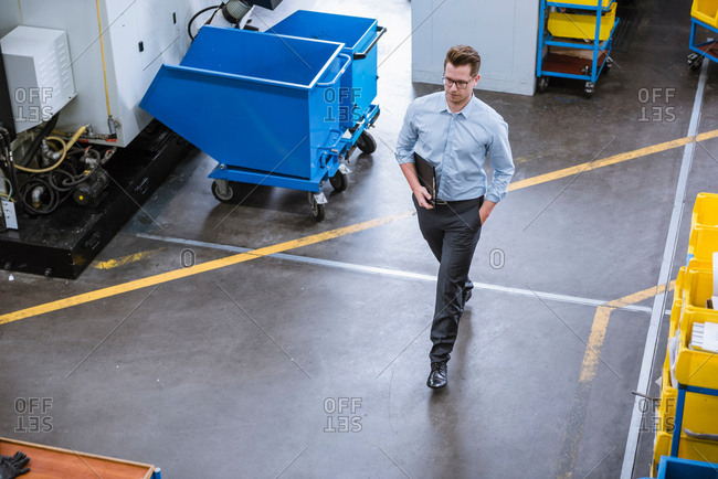 High angle view of male manager with clipboard walking in factory