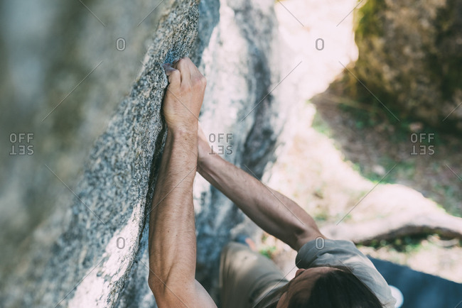 High angle view of young male boulderer gripping boulder, Lombardy, Italy