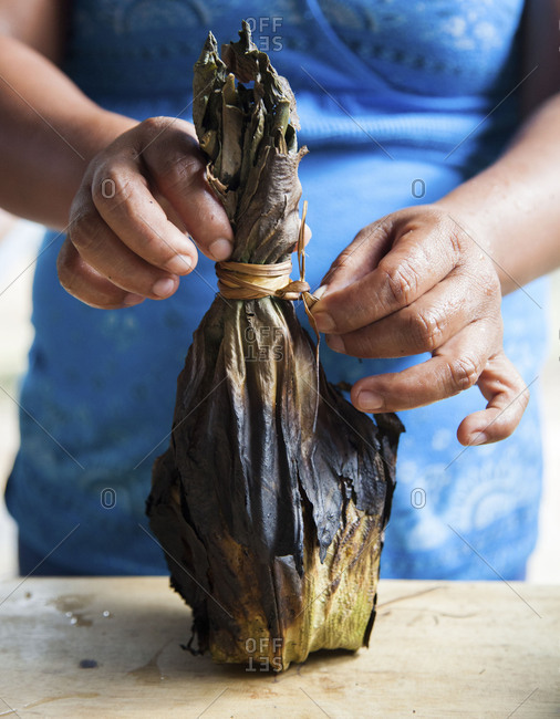 Woman untying a charred stuffed banana leaf