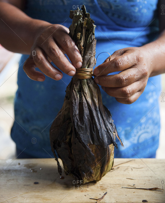 Woman opening a charred stuffed banana leaf