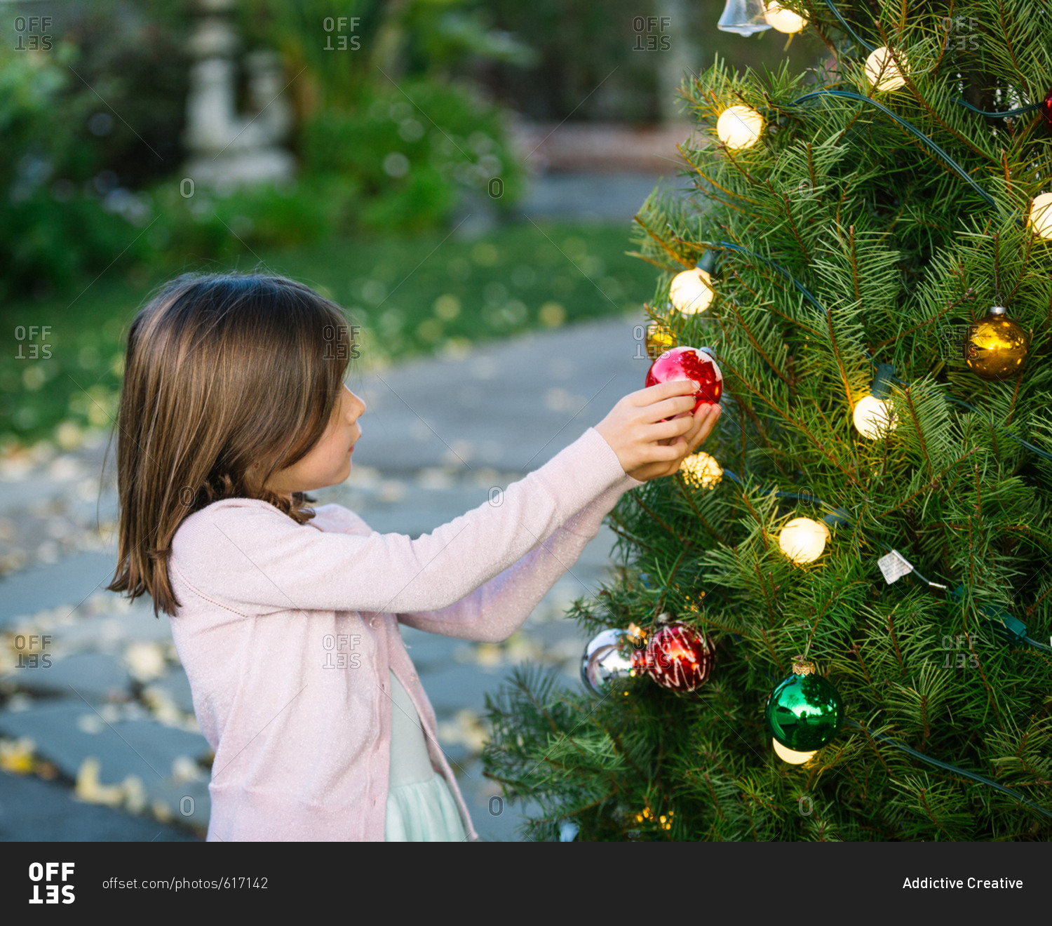 Little Adorable Girl decorating Christmas Tree stock photo OFFSET