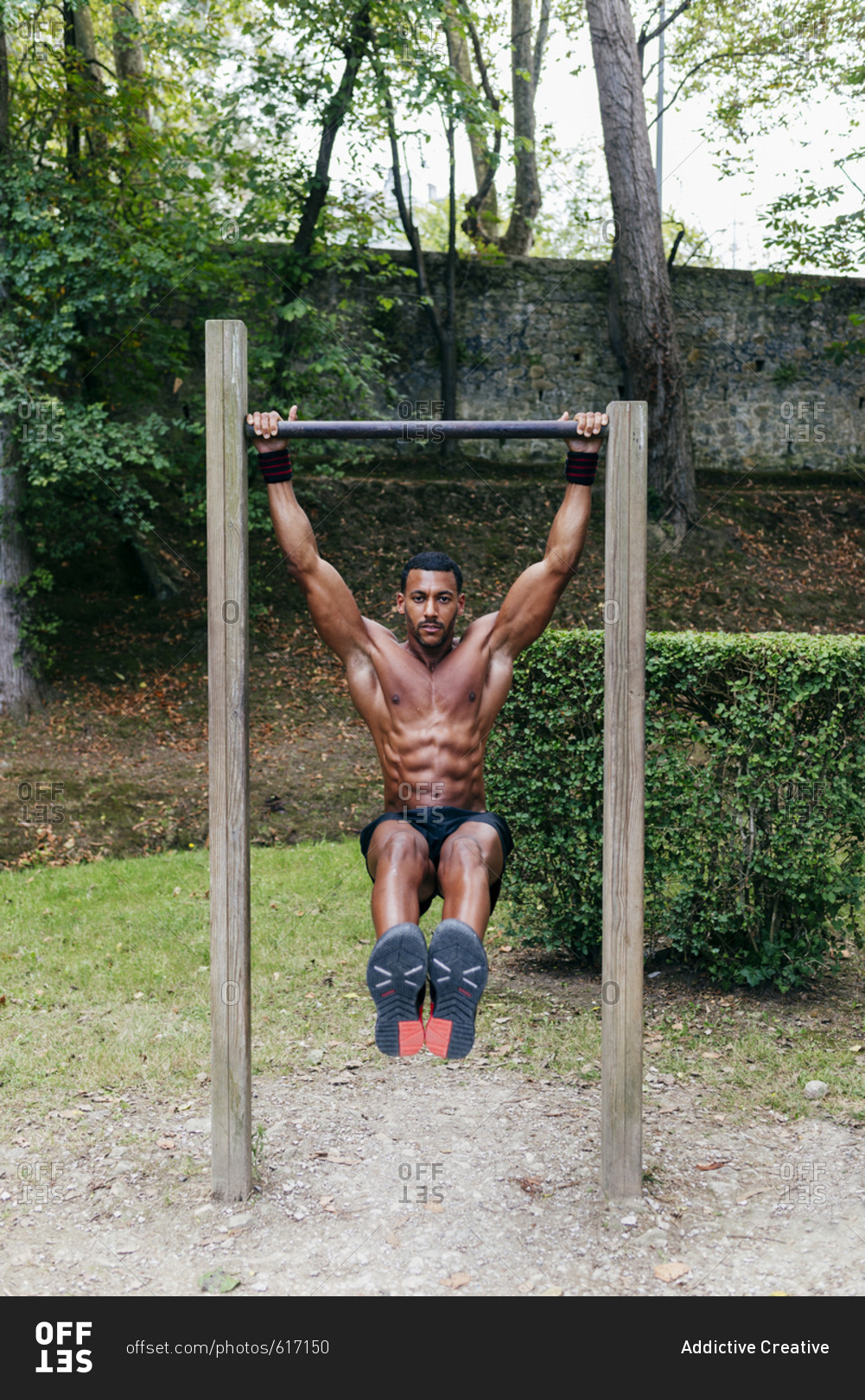 Athletic muscular black man hanging on bar during the workout.