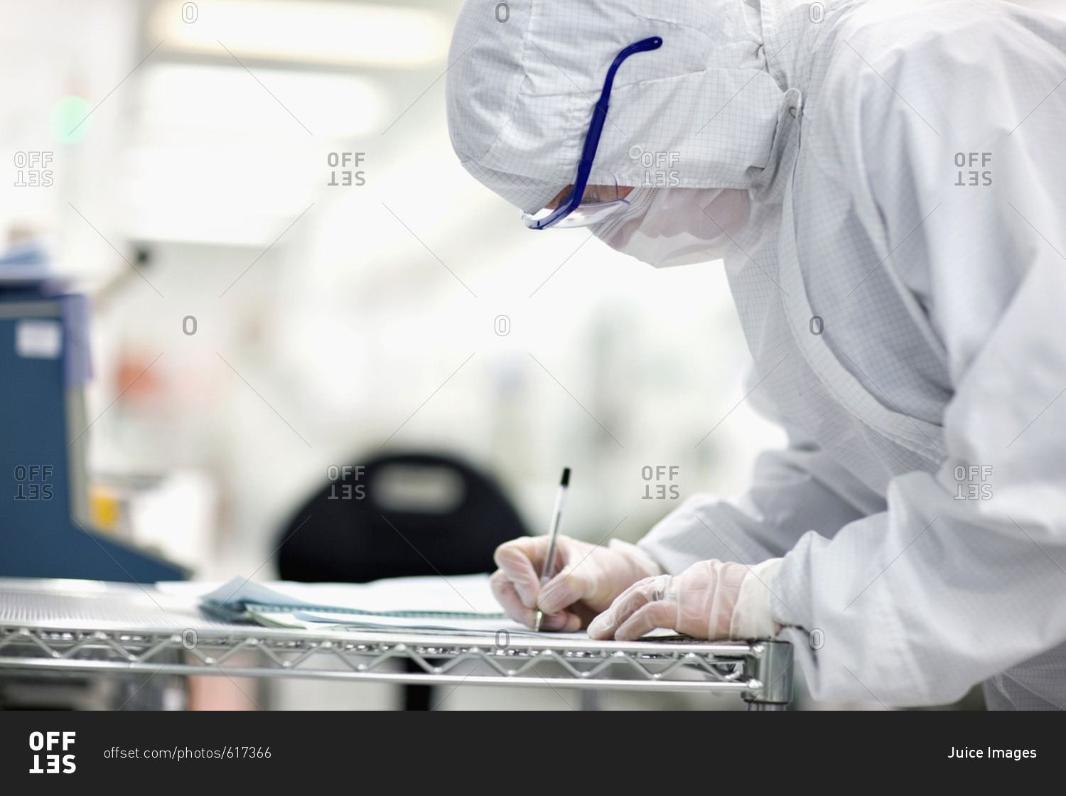 Engineer in clean suit taking notes in silicon wafer manufacturing laboratory