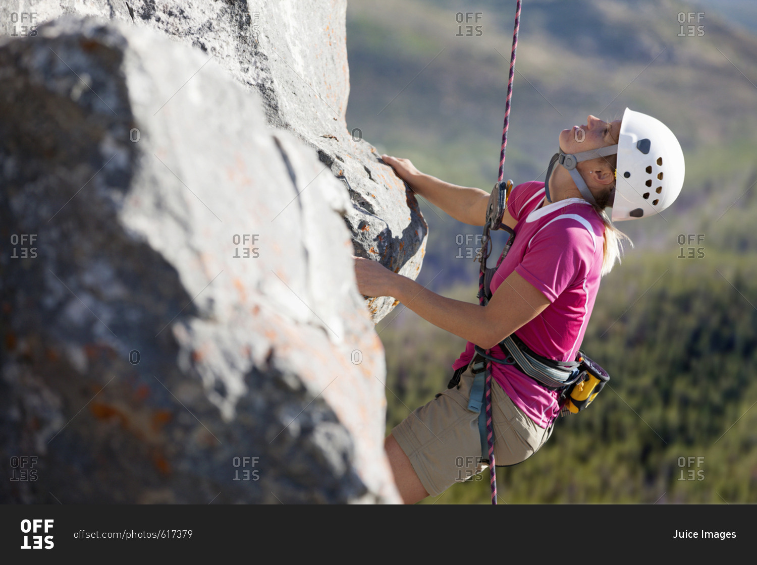 Female rock climber scaling rock face and looking up