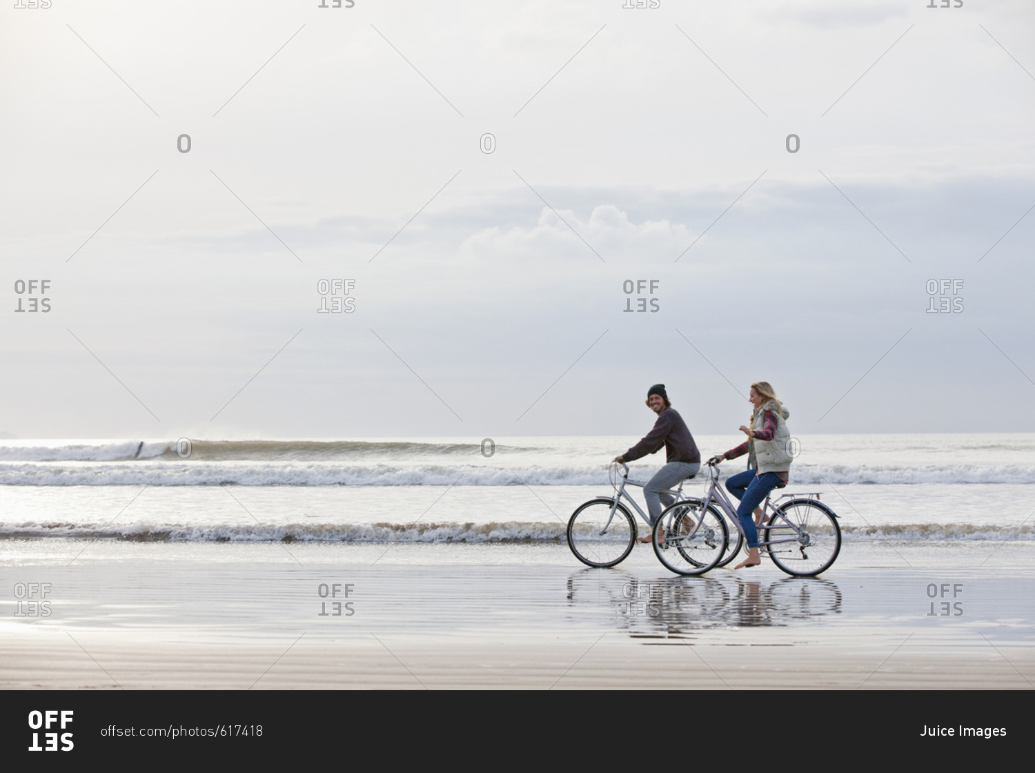 Couple riding bicycles in ocean surf