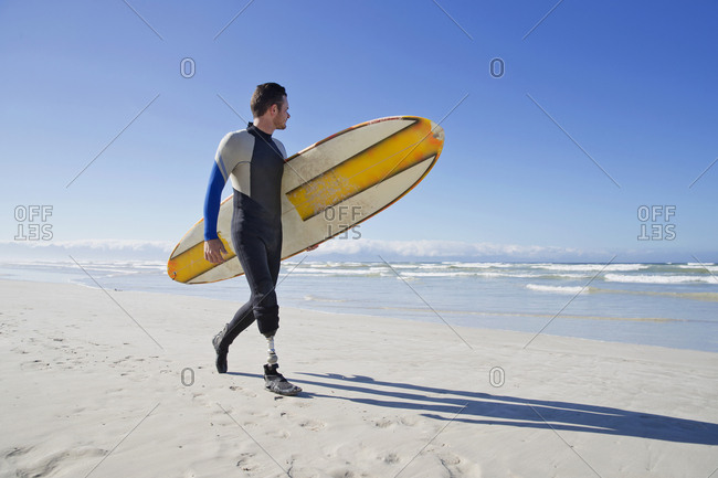 Surfer With Artificial Leg Standing On Beach
