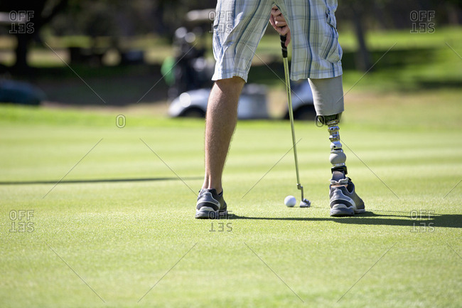 Close Up Of Male Golfer With Artificial Leg Putting Ball On Green