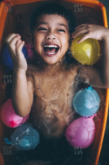 Happy boy in a tub filled with water balloons