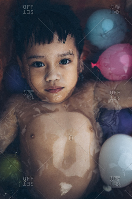 Boy in a pool filled with water balloons