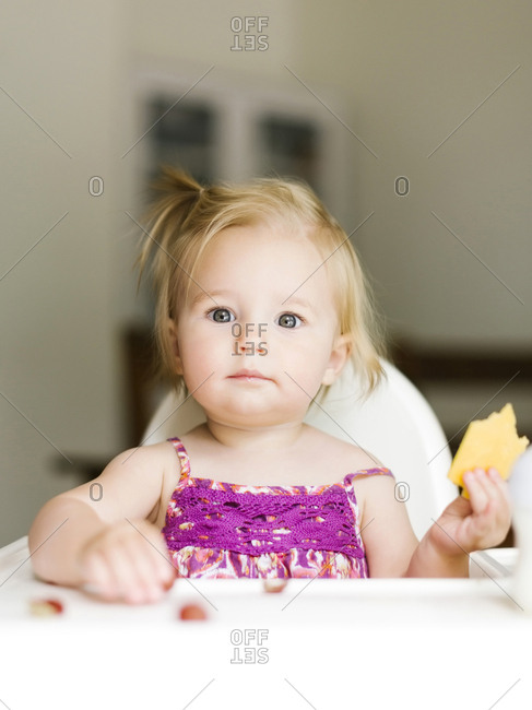 Portrait of baby girl (12-17 months) eating lunch