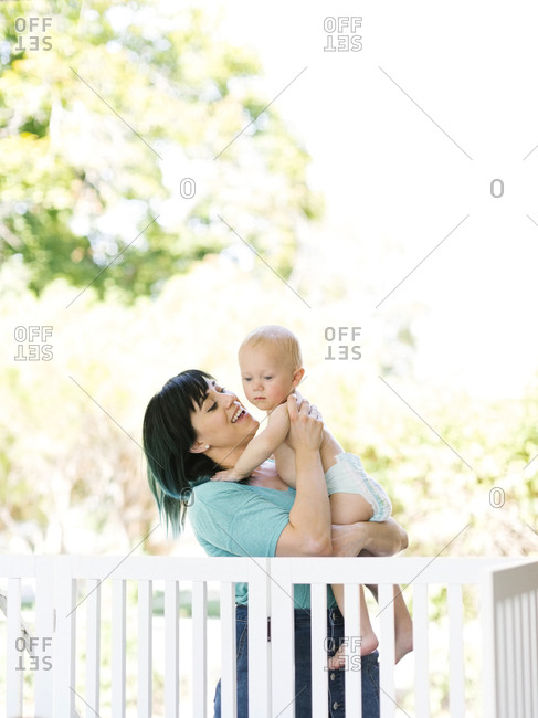 Mother carrying baby boy (12-17 months) on porch
