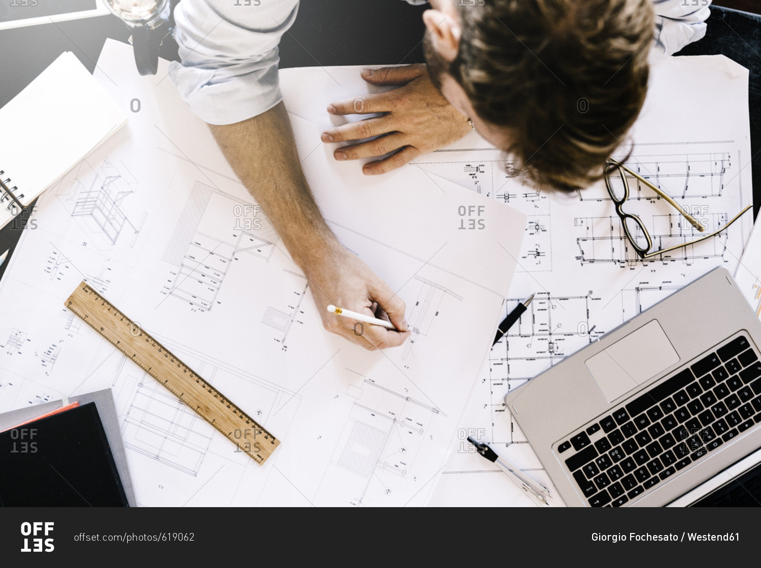 Man working on construction plan at desk- top view
