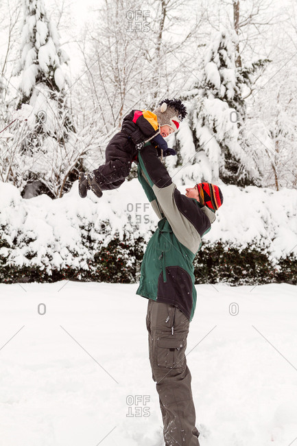 Father lifting baby in the air in winter outdoors